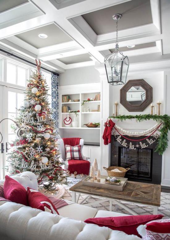ονειρεμένες χριστουγεννιάτικες διακοσμήσεις στο σαλόνι λευκός καναπές κόκκινα μαξιλάρια έλατο πράσινη γιρλάντα δίπλα στο τζάκι