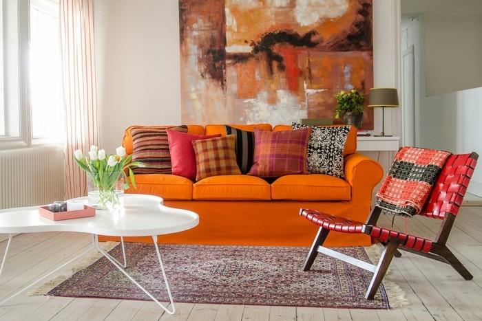 τοιχογραφίες σαλόνι πορτοκαλί καναπές ρίξτε μαξιλάρια χαλί ξύλινο πάτωμα