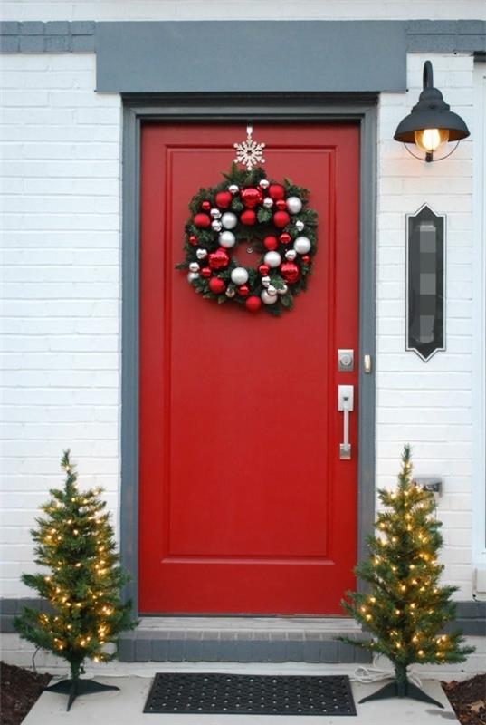 χριστουγεννιάτικη διακόσμηση σπίτι είσοδος κόκκινη μπροστινή πόρτα όμορφο χριστουγεννιάτικο στεφάνι λαμπερά έλατα