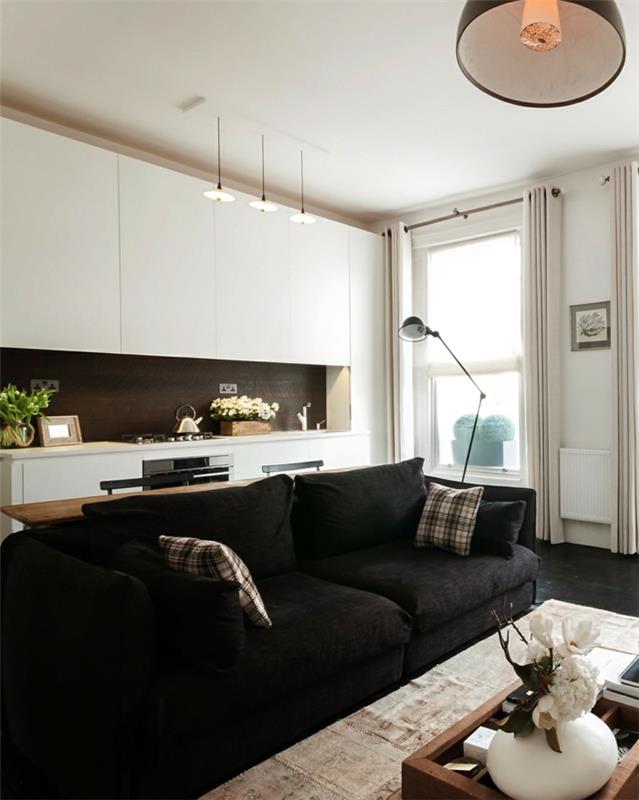 κουζίνα με λευκά ντουλάπια κουζίνας και μαύρο καναπέ σαλόνι