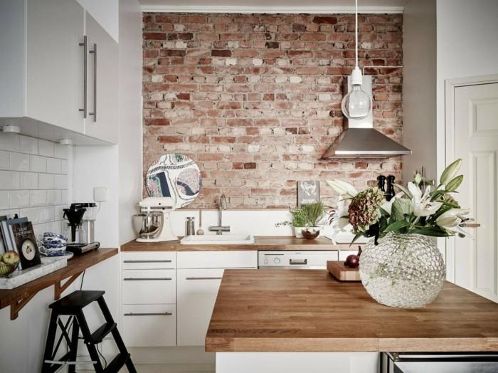 Τουβλότοιχος στην κουζίνα σε συνδυασμό με λευκά πλακάκια τοίχου και ξύλινη επιφάνεια εργασίας